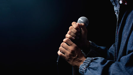 Man hands holding microphone on stand.