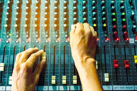 Men's hands on the mixing console in the conference room.