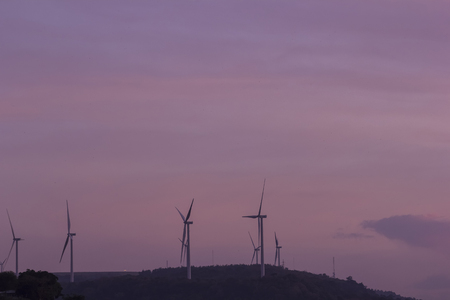 Silhouette of wind turbines generating electricity on the mountain.の写真素材