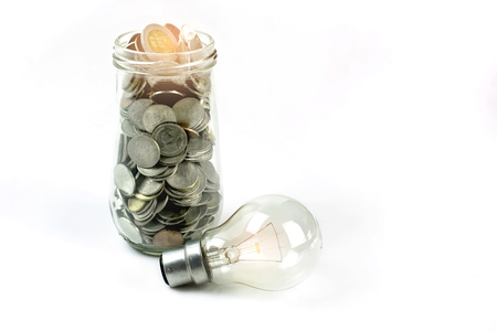 Concept of using energy efficiently or enhancing working power. Tungsten lamps and coins in glass bottles.の写真素材