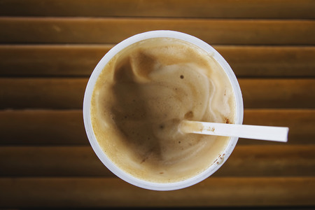 Top view of coffee in a white plastic coffee mug on a wooden table.の写真素材