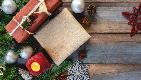 Amidst the cozy embrace of the holiday season, a tableau of Christmas decorations takes center stage against a rustic wooden background, offering a visual symphony of festive delight and anticipation. The rich, textured backdrop serves as the perfect canvas for the yuletide treasures that adorn it, while leaving ample copy space for holiday messages and well-wishes.の素材