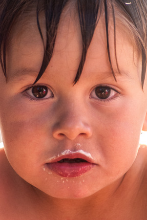 A little hispanic boy with frosting mustache, close upの写真素材