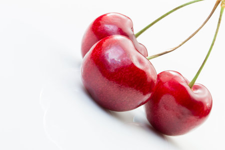 Three cherries with stems on a white background.
