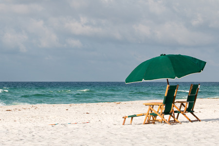 Beach umbrella and chairs on a white sand beach.の写真素材