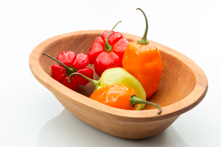Habanero peppers in a wooden bowl on white background.の写真素材
