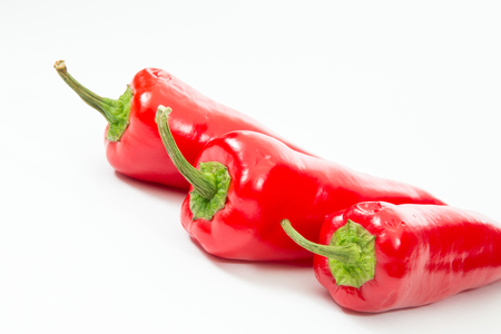 Three red chili peppers on a white background.の写真素材