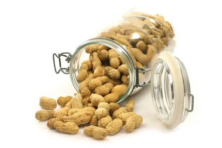 glass bottle with lots of peanuts on a white background の写真素材