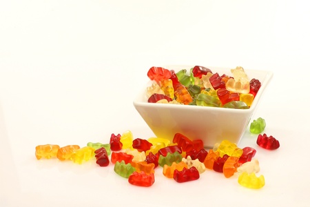 colorful gummy bears in a white bowl on a white background の写真素材