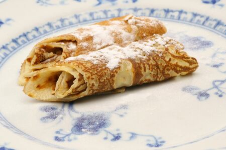 pancakes sprinkled with a layer of powdered sugar on a plate on a white background の写真素材