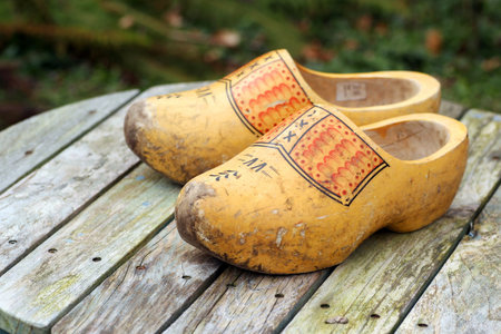 pair of traditional Dutch yellow wooden shoes on a wooden table 