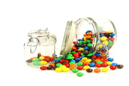 colorful sweets in a glass jar on a white backgroundの写真素材