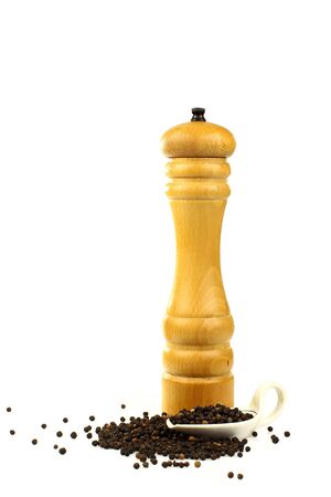 wooden pepper mill with black pepper in a measuring cup の写真素材