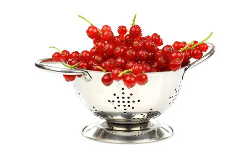 metal colander with a bunch of red currant on a white background の写真素材