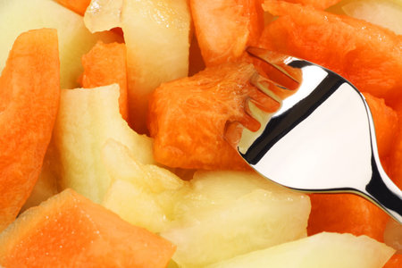colorful mix of delicious melon pieces with a fork backgroundの写真素材
