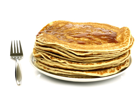 a plate with stacked freshly baked pancakes with a fork on a white background 