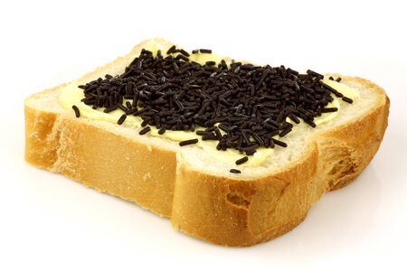 sliced white bread with butter and chocolates sprinkles on a white background の写真素材