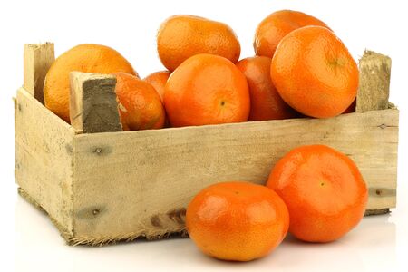 bunch of fresh tangerines in a wooden box on a white background の写真素材
