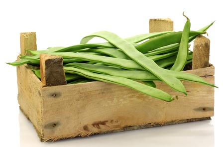 bunch of string beans in a wooden box on a white backgroundの写真素材
