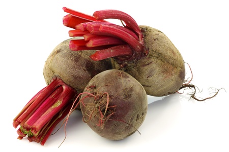 three beetroots with part of foliage on a white background の写真素材