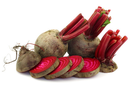 two whole beetroots and a cut one on a white background 