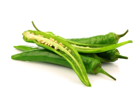 bunch of fresh green chili peppers and two halves on a white background の写真素材