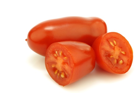 one whole italian tomato and two halves on a white background の写真素材