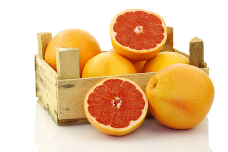 fresh red grapefruits in a wooden box on a white background の写真素材