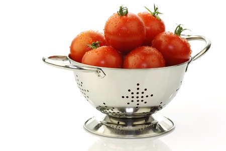 fresh tomatoes in a metal colander on a white background の写真素材