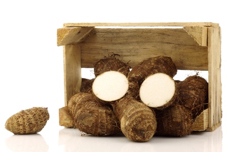 bunch of taro root  colocasia  in a wooden crate on a white background の写真素材