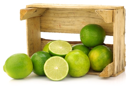 fresh lime fruit in a wooden crate on a white background の写真素材
