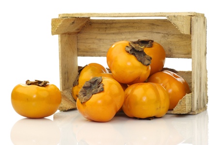 fresh kaki fruit in a wooden crate on a white backgroundの写真素材