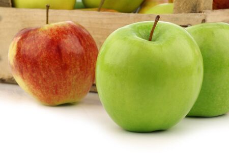 assorted fresh apples in a wooden crate on a white background の写真素材