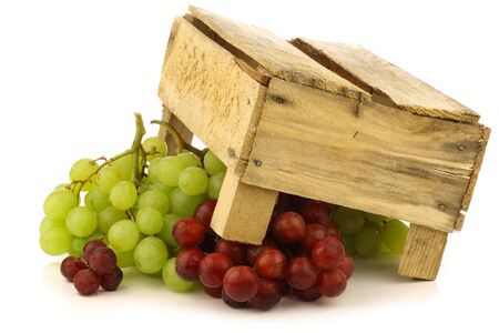 red and white grapes under wooden crate on a white background の写真素材