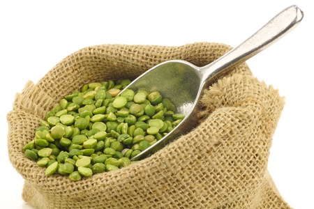 split green peas in a burlap bag with an aluminum scoop on a white background の写真素材