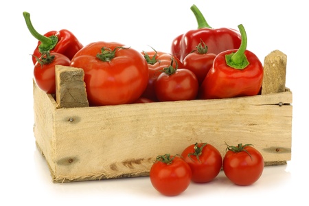 red sweet peppers and tomatoes in a wooden crate on a white background の写真素材