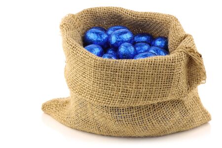 colorful chocolate easter eggs in a burlap bag on a white background の写真素材