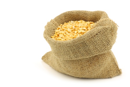 yellow split peas in a burlap bag on a white background の写真素材
