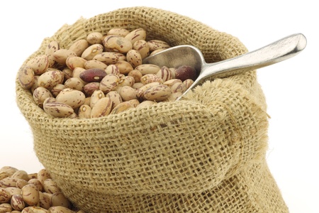 speckled beans in a burlap bag with an aluminum scoop on a white background の写真素材