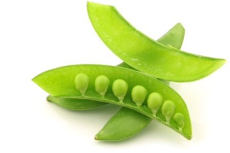 bunch of sugar snaps with one opened pod with peas visible on a white background の写真素材