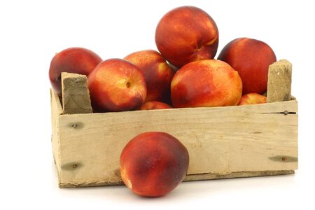 fresh nectarines in a wooden crate on a white backgroundの写真素材