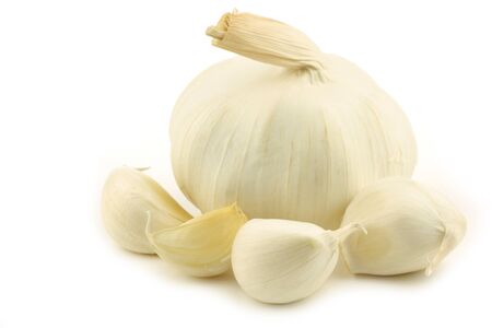  one whole dried garlic bulb and some cloves on a white backgroundの写真素材