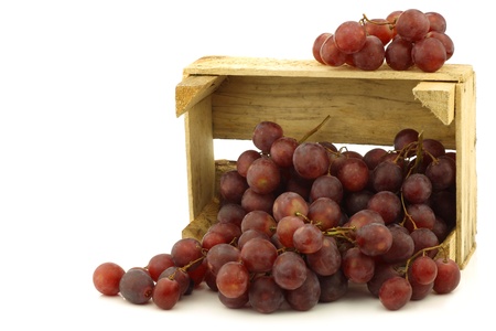 fresh red seedless grapes on the vine in a wooden crate on a white backgroundの写真素材