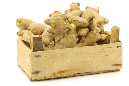 dried pieces of ginger root in a wooden crate on a white backgroundの写真素材