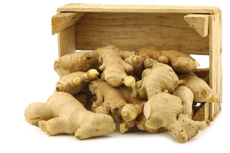 dried pieces of ginger root in a wooden crate on a white backgroundの写真素材