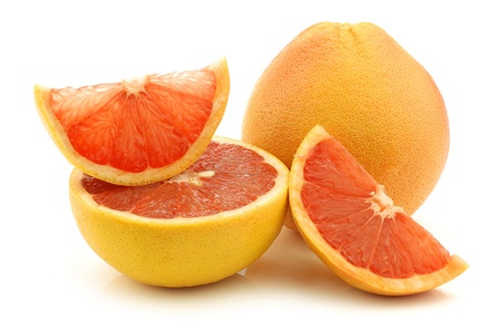 fresh red grapefruit and some cut pieces on a white backgroundの写真素材