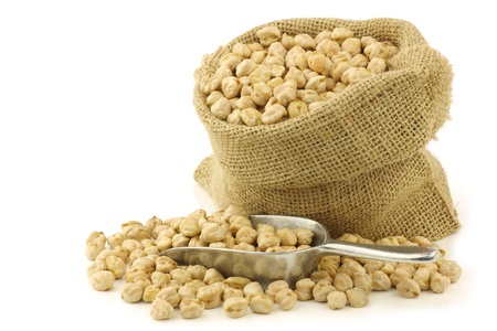 dried chick peas in a burlap bag with an aluminum scoop on a white backgroundの写真素材