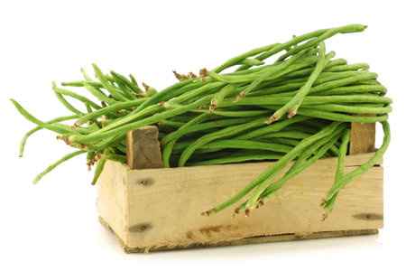 fresh long beans Vigna unguiculata subsp  sesquipedalis  in a wooden crate on a white background