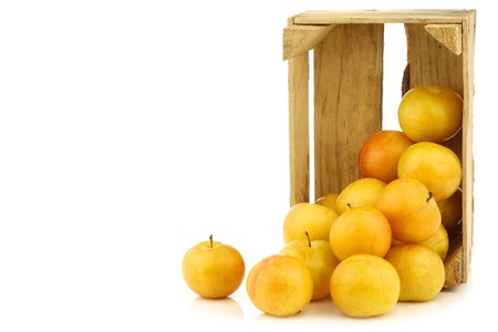 fresh yellow plums in a wooden crate ona white backgroundの写真素材