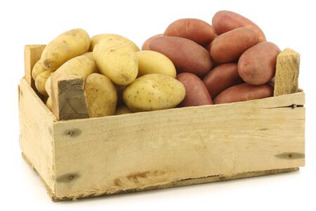 small red and yellow potatoes in a wooden crate on a white backgroundの写真素材